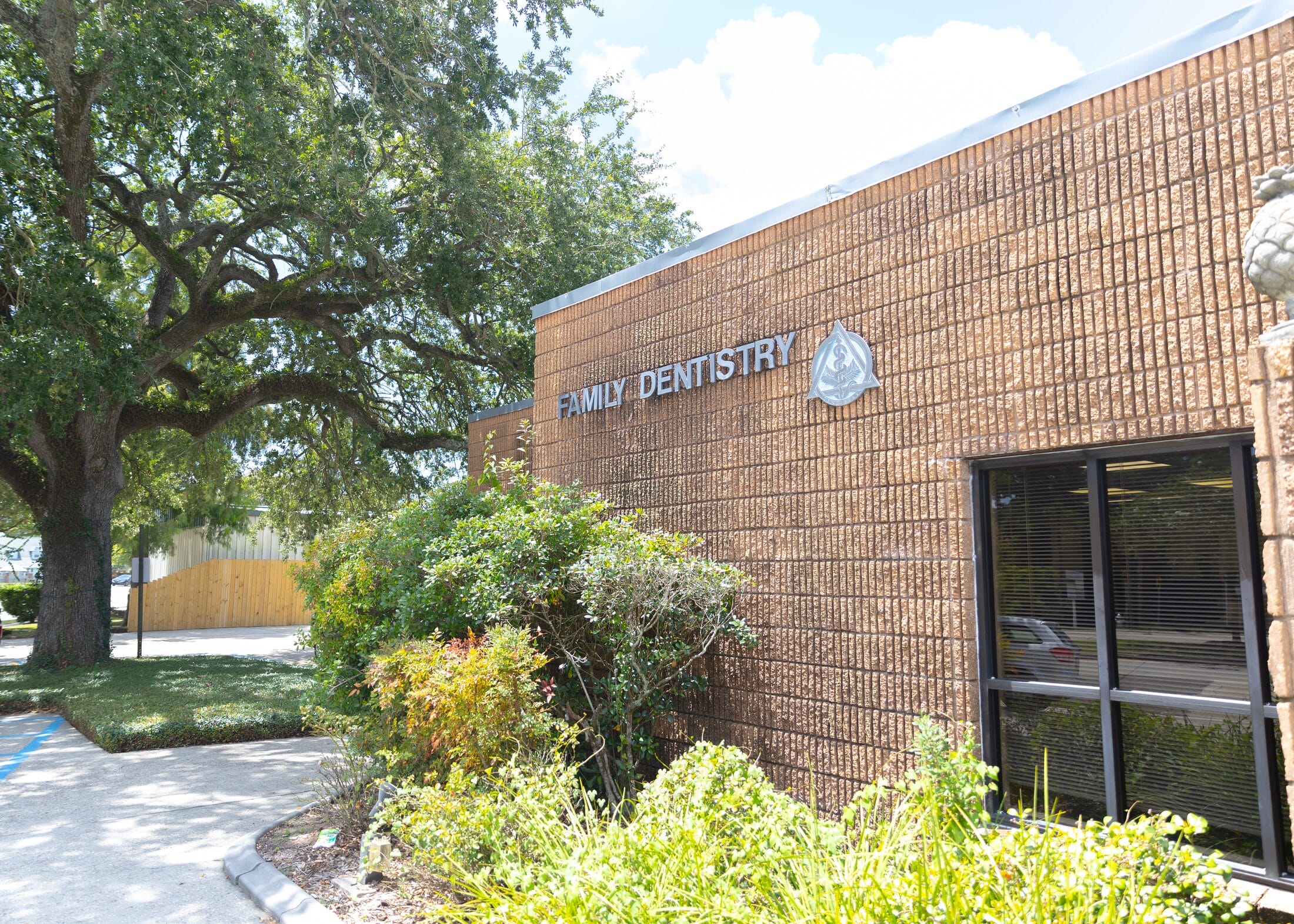 The live oak’s canopy over the Family Dentistry sign on Barataria Dental’s brick front