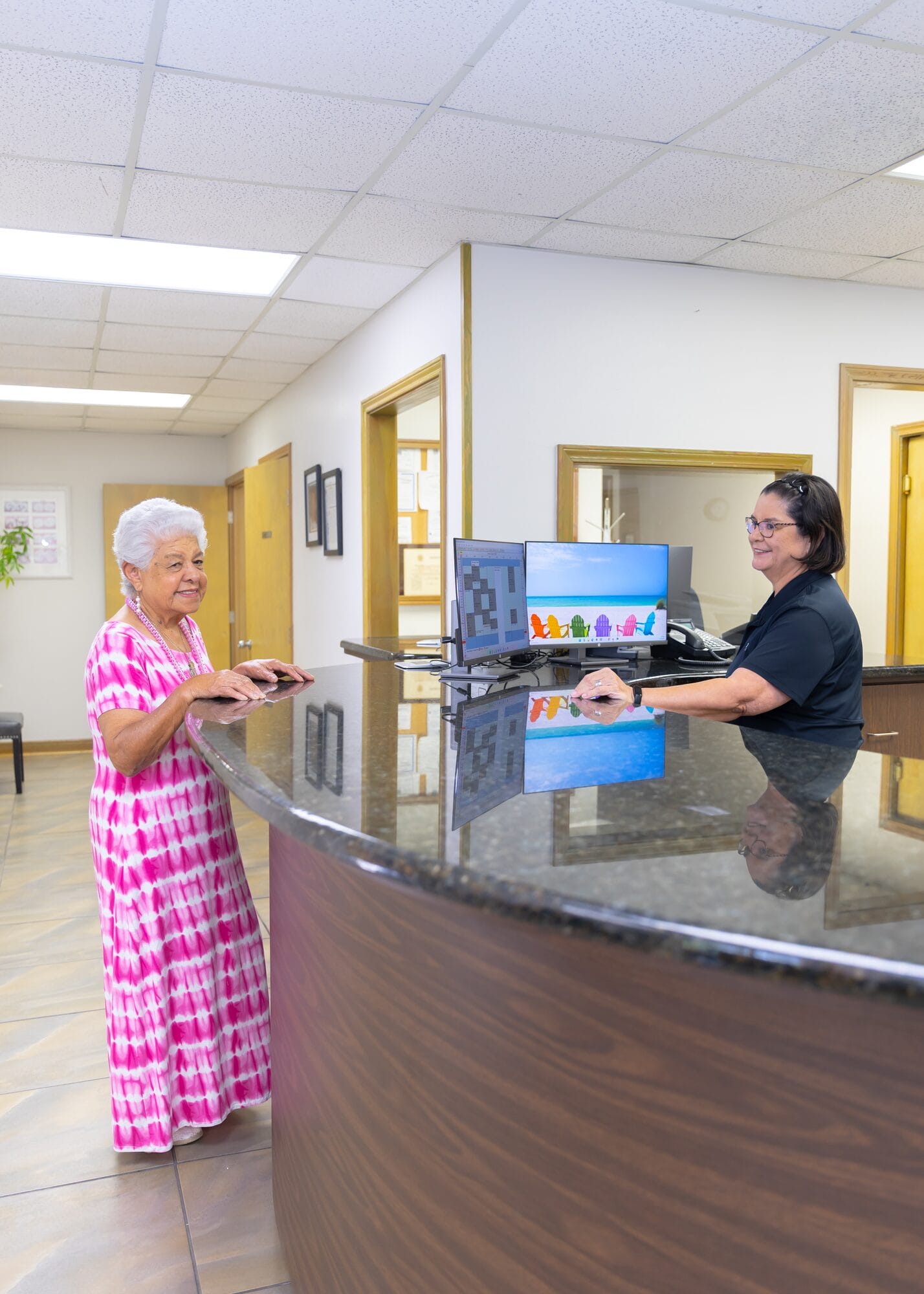 A Barataria Dental team member at the front desk, smiling across the counter at a patient