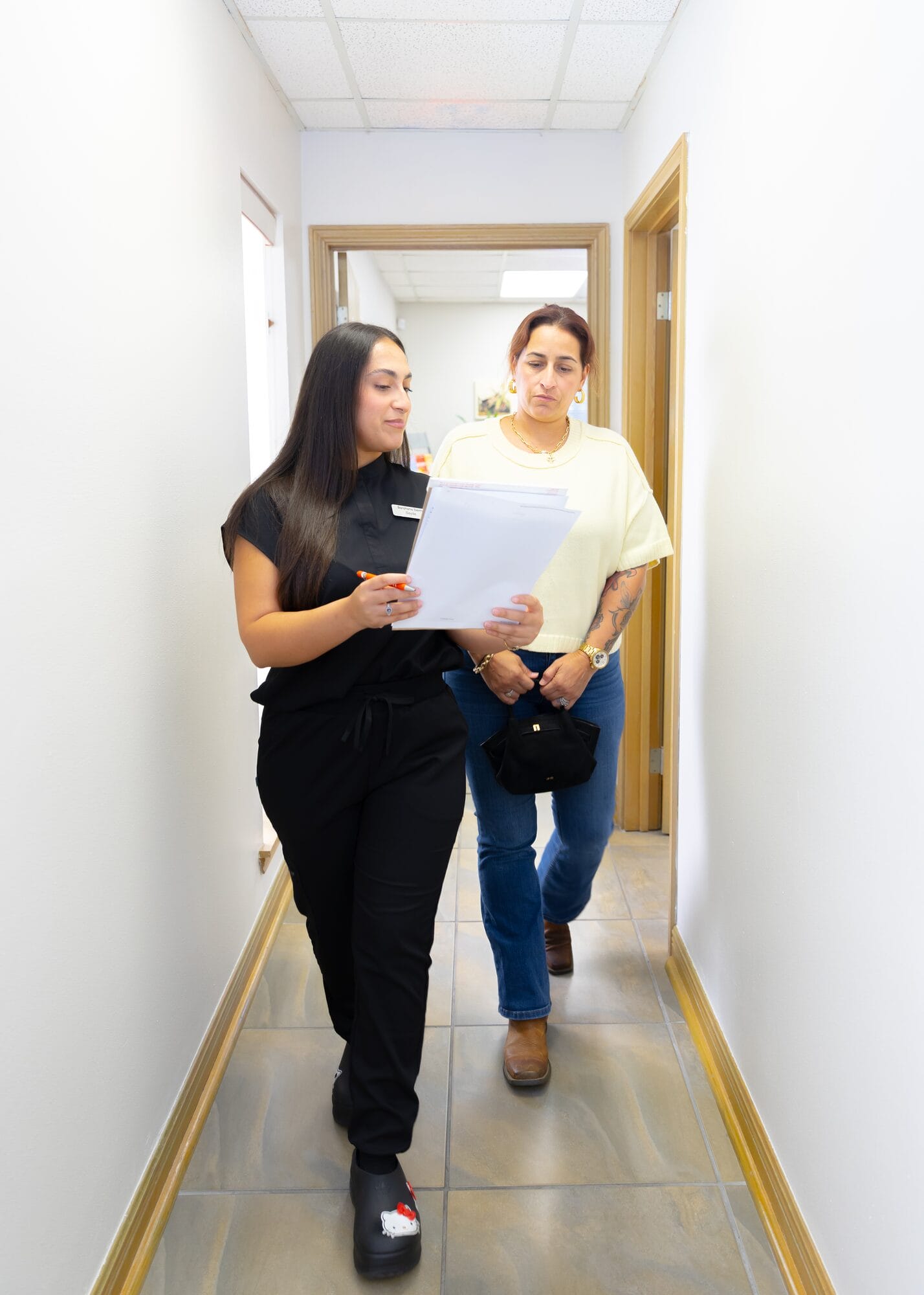 A Barataria Dental team member going over paperwork with a patient as they walk down the office hallway