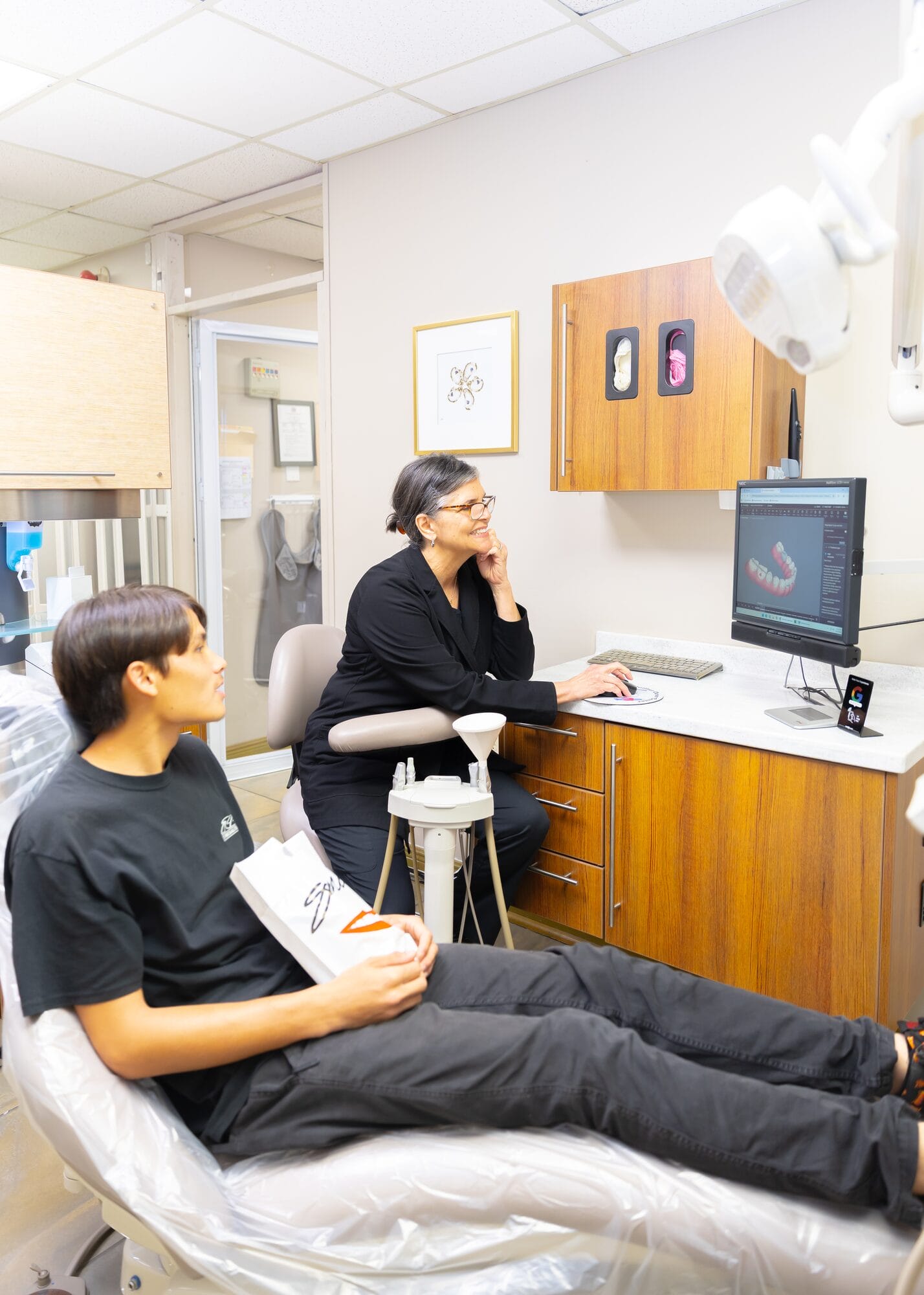 A Barataria Dental dentist reviewing a scan on the operatory screen with a teenage patient in the chair