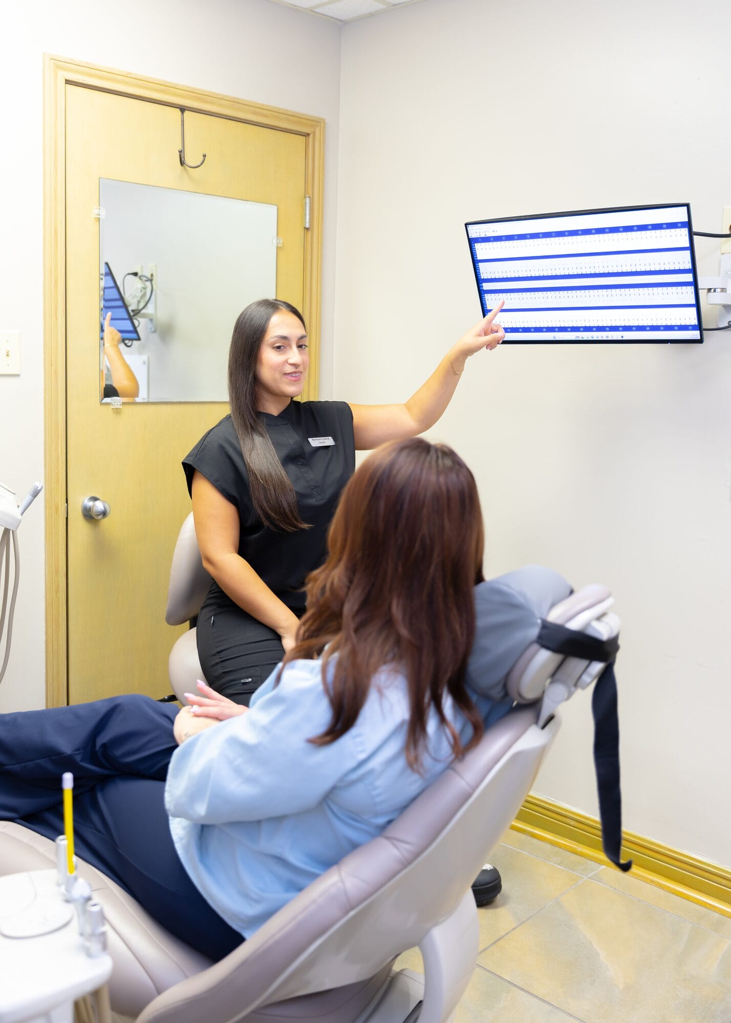 A Barataria Dental team member explaining a chart to a patient in the operatory chair
